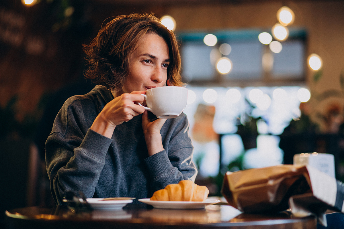 young woman eating croissants cafe