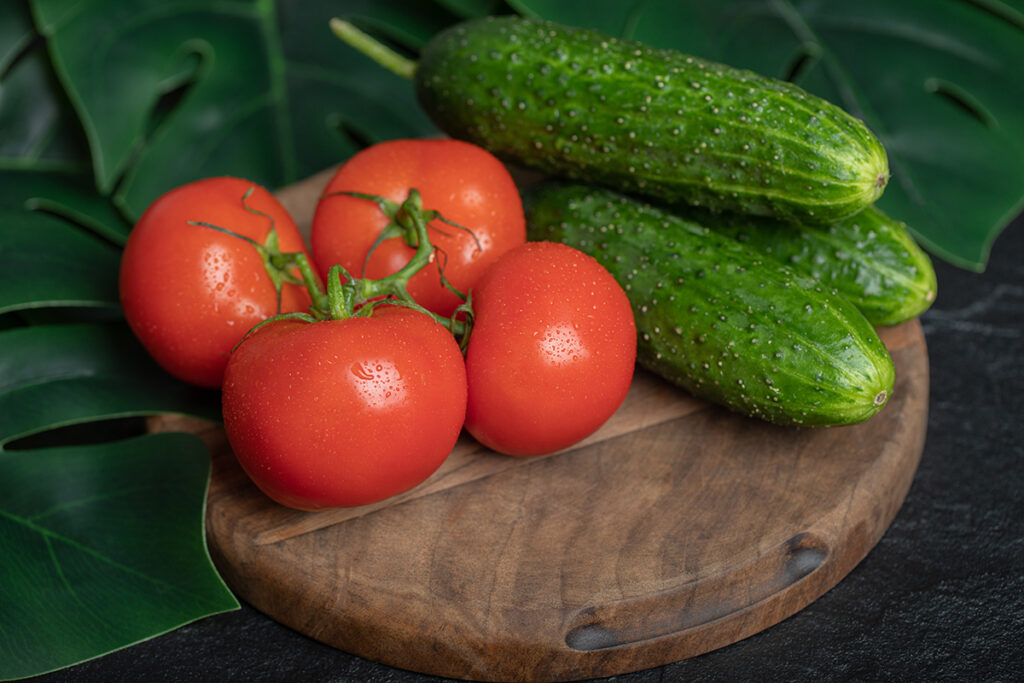 pile fresh organic vegetables cucumbers tomatoes wooden board with green leaves