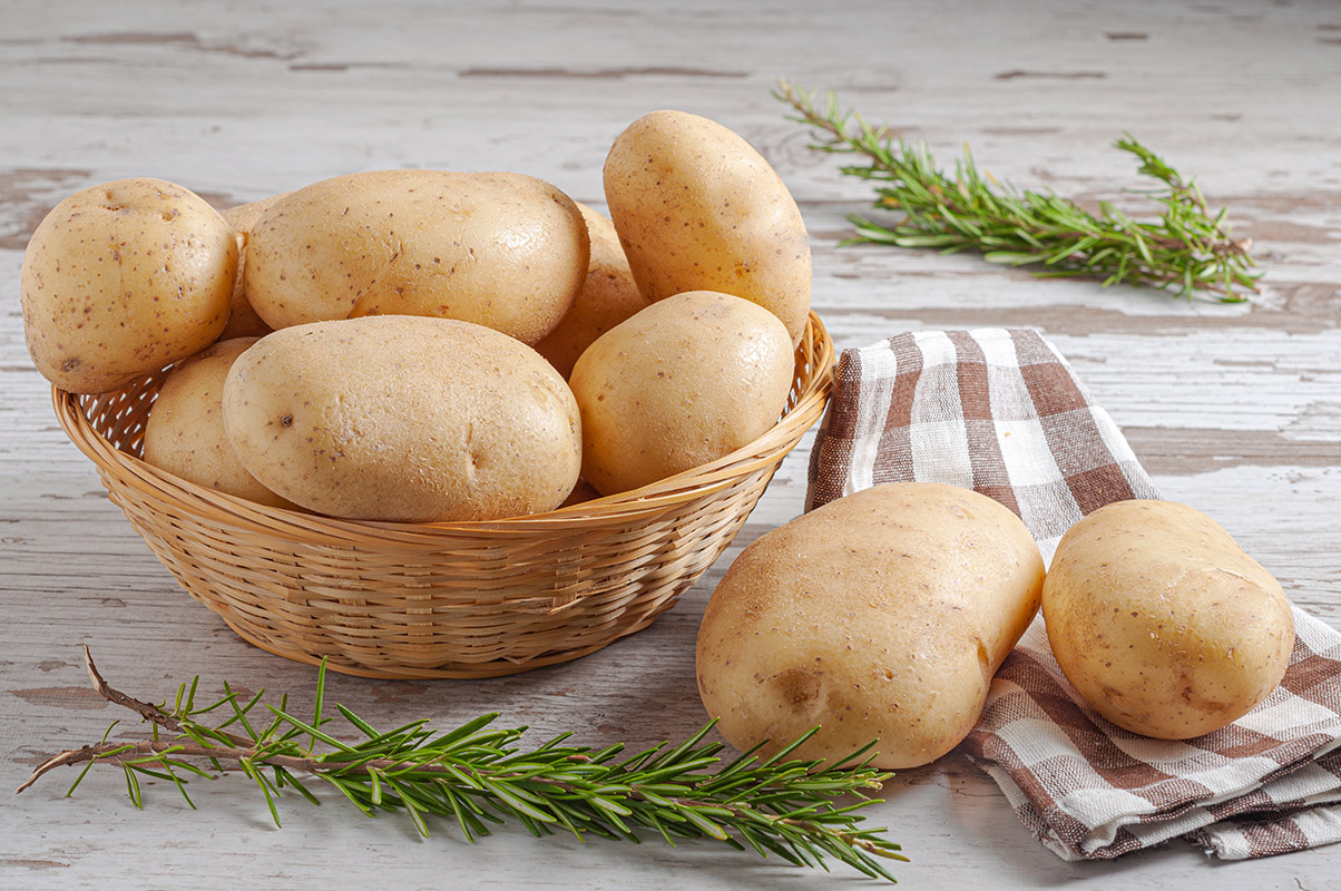 syroi kartofel v pletenoi korzine s natural nymi list ami rozmarina na derevannom derevenskom stole
