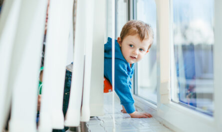small boy stands near window sill 1