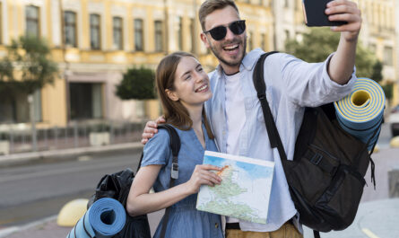 smiley tourist couple taking selfie while carrying backpacks