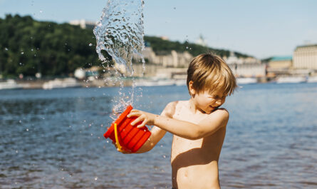 young boy spills water from bucket sea beach