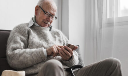 side view older man nursing home using smartphone