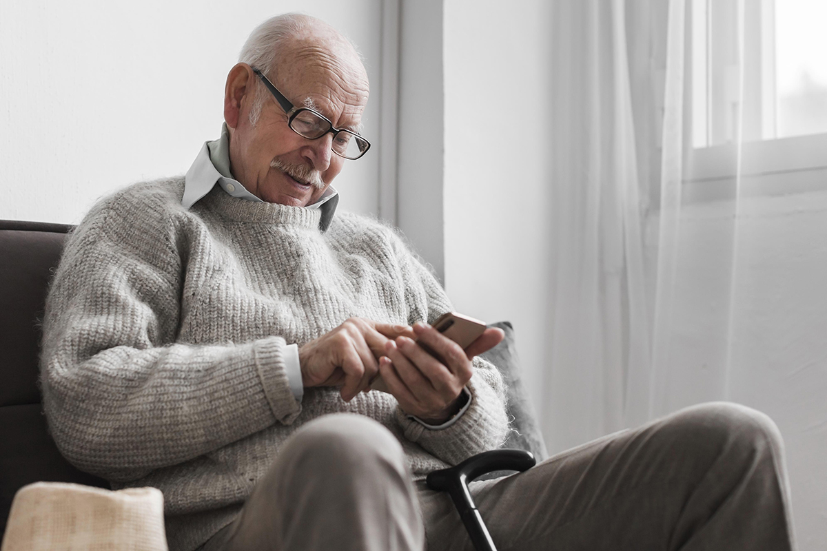 side view older man nursing home using smartphone