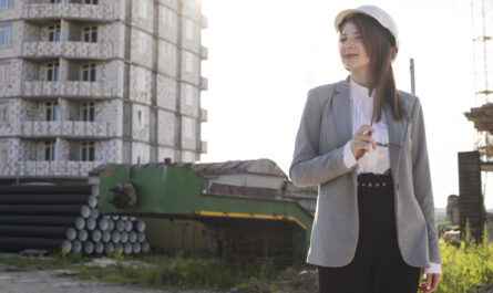 smiling woman holding spectacle standing construction site looking away 1
