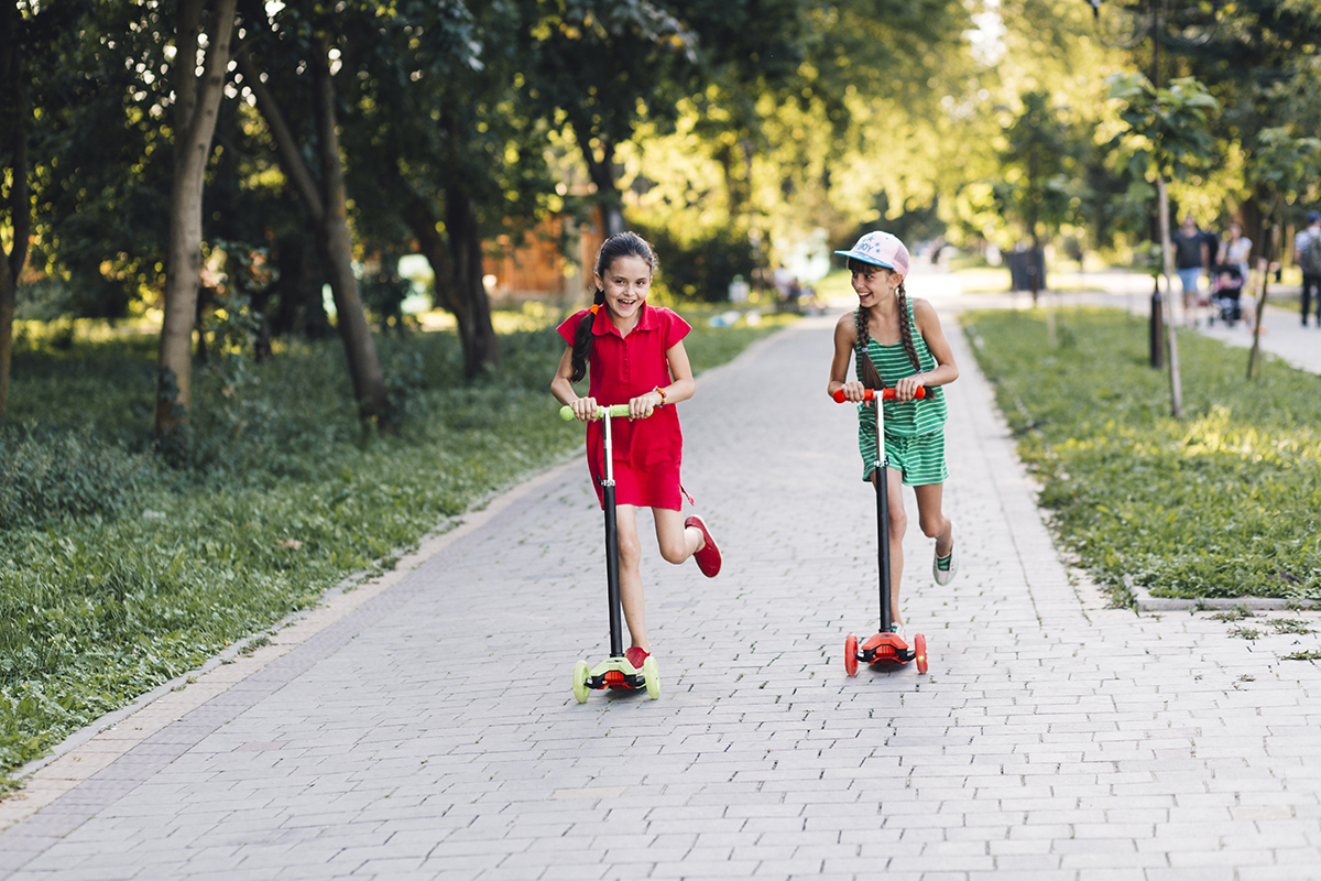 two girls enjoying riding push scooter park