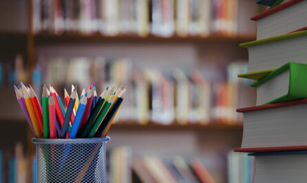close up colored pencils with books