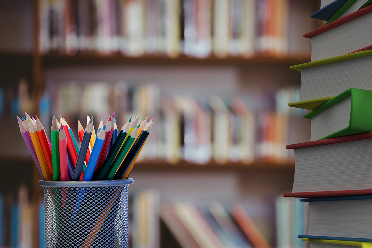 close up colored pencils with books