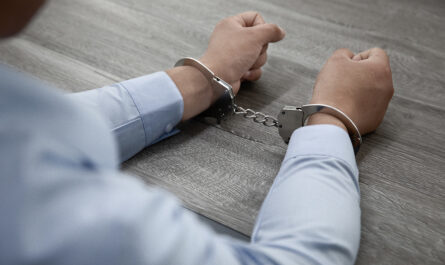 selective focus shot male hands handcuffs wooden table