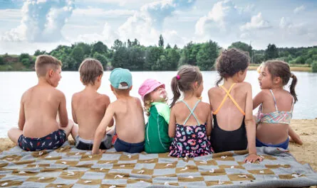 back view children sit near river relax after swimming sunbathe eat ice cream