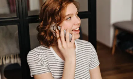 closeup portrait red curly girl striped t shirt talking phone
