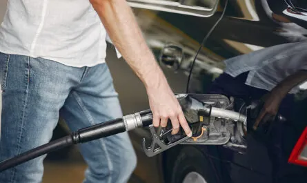 handsome man pours gasoline into tank car