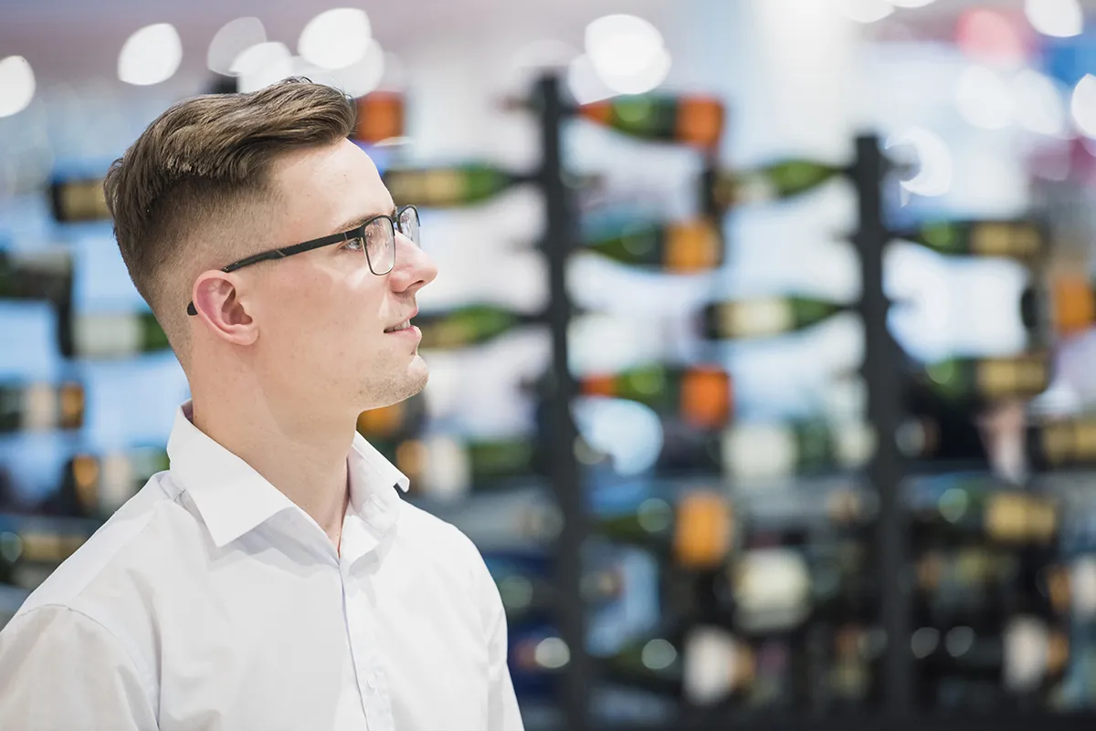 portrait smiling young man standing front arranged bar bottles