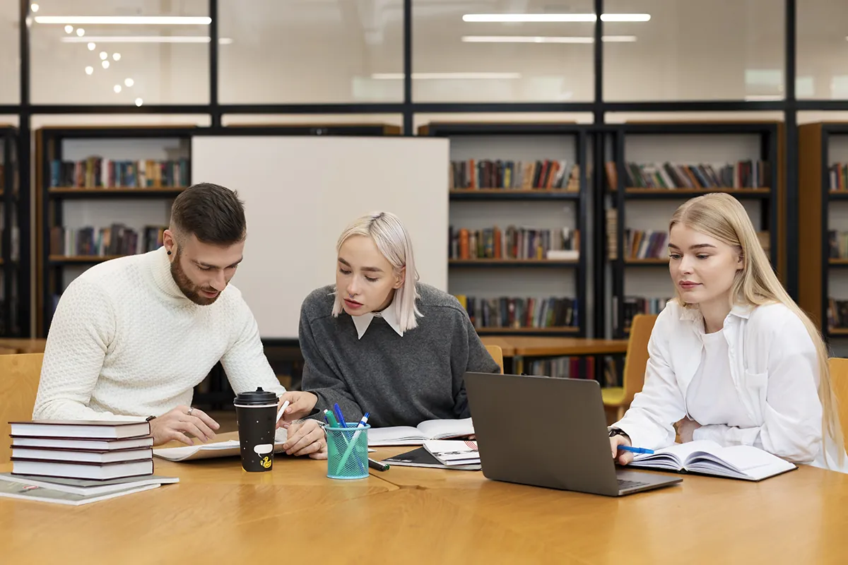 three friends studying from documents laptop library