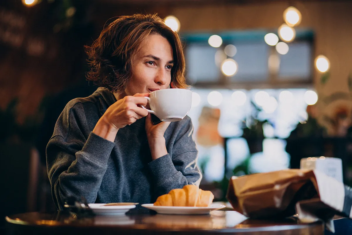 young woman eating croissants cafe