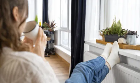 krupnyi plan zensiny sidasei vozle obogrevatela